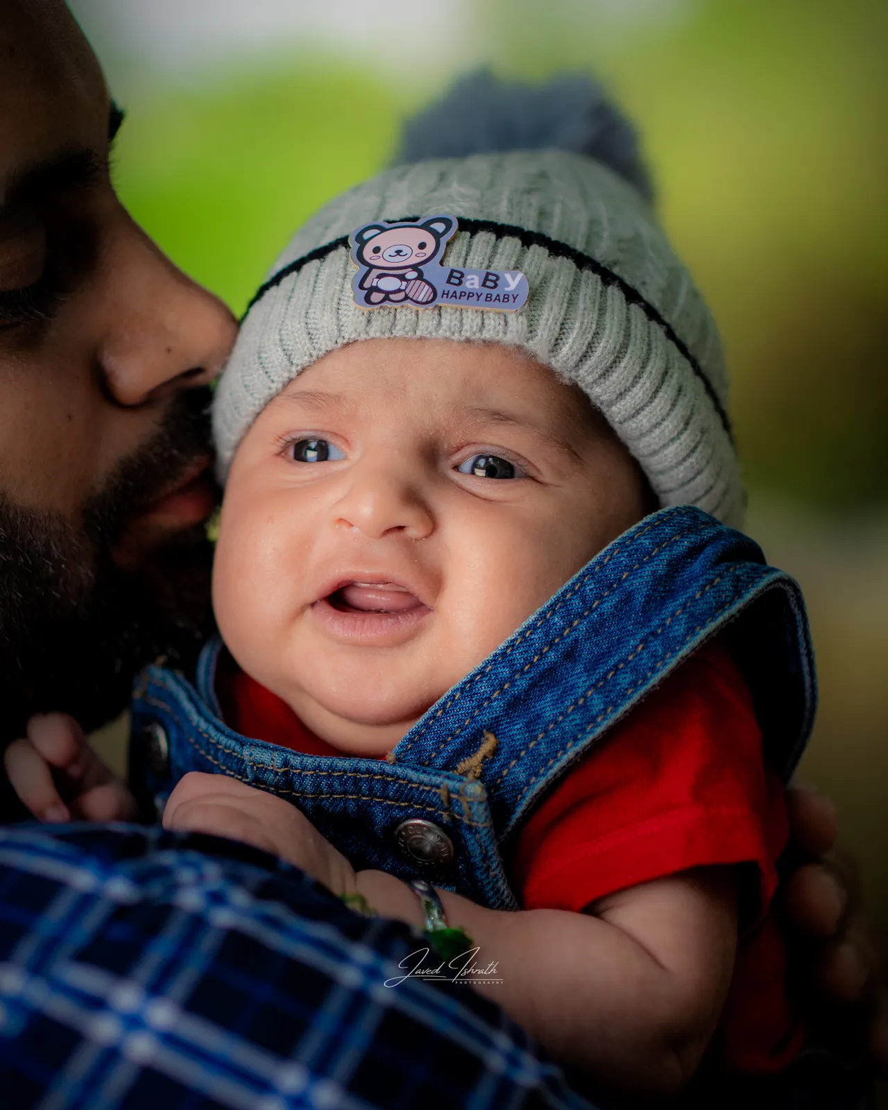 A father kissing his newborn in a knitted hat